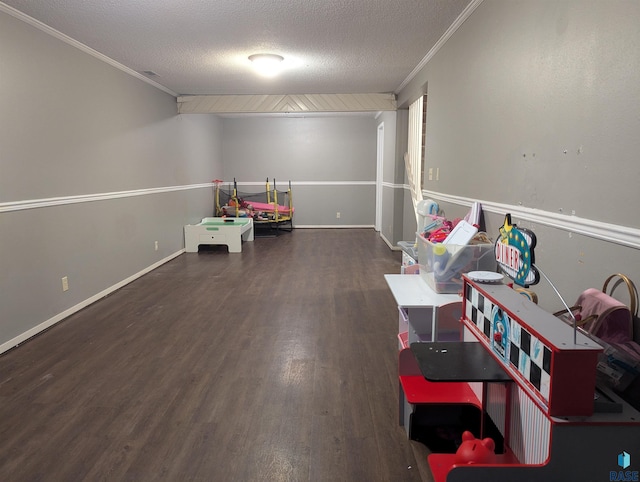 recreation room with a textured ceiling, crown molding, and dark wood-type flooring