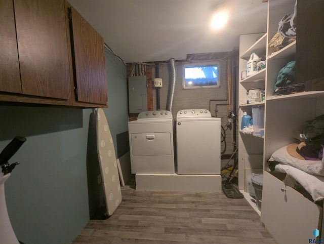 laundry area featuring electric panel, cabinets, light hardwood / wood-style flooring, and washer and dryer