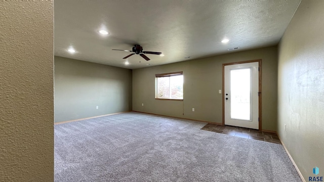 carpeted spare room featuring a textured ceiling and ceiling fan