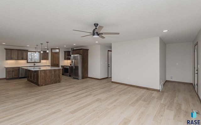 kitchen with sink, ceiling fan, light wood-type flooring, appliances with stainless steel finishes, and a kitchen island