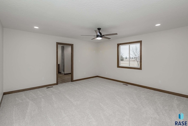 carpeted empty room with ceiling fan and a textured ceiling