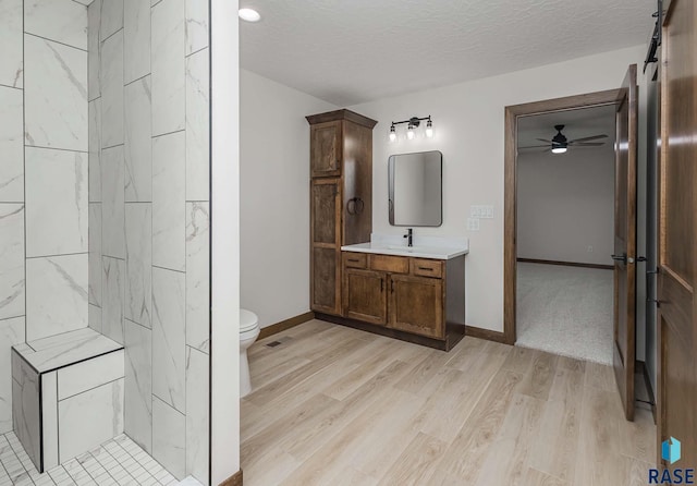 bathroom featuring vanity, ceiling fan, toilet, a textured ceiling, and wood-type flooring