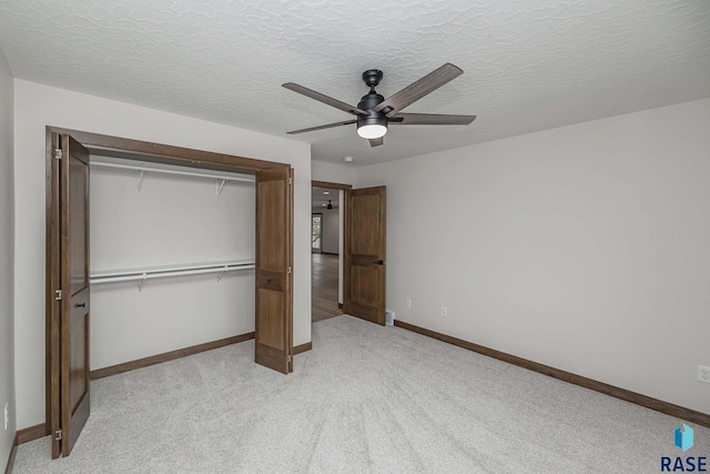 unfurnished bedroom with ceiling fan, a closet, light carpet, and a textured ceiling