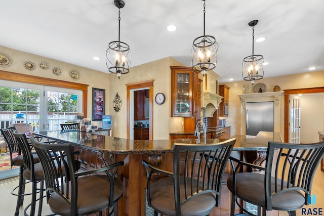 kitchen with a kitchen bar, pendant lighting, stainless steel built in refrigerator, and custom exhaust hood