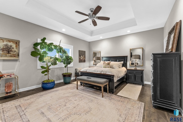 bedroom with a raised ceiling, ceiling fan, and dark wood-type flooring