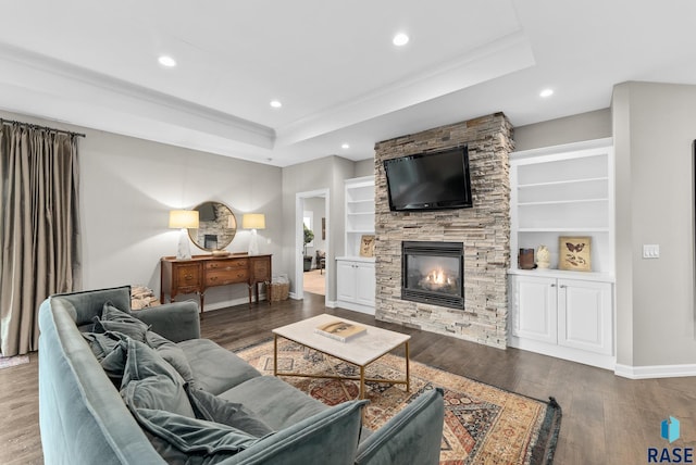 living room with a fireplace, built in shelves, a tray ceiling, and hardwood / wood-style flooring