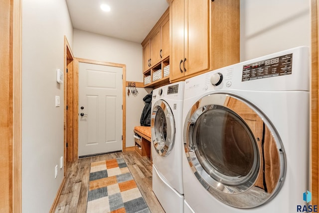 laundry area featuring cabinets, light hardwood / wood-style floors, and washer and clothes dryer