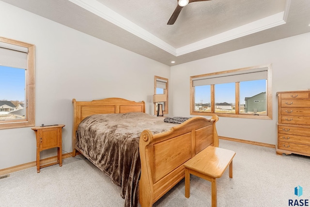 carpeted bedroom featuring a tray ceiling, ceiling fan, and crown molding