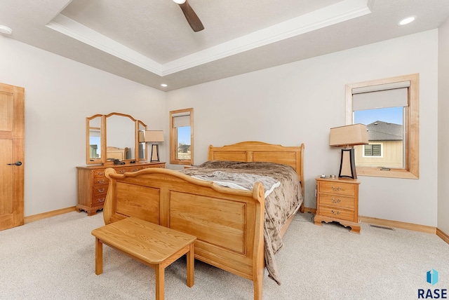 carpeted bedroom with a tray ceiling, ceiling fan, and crown molding