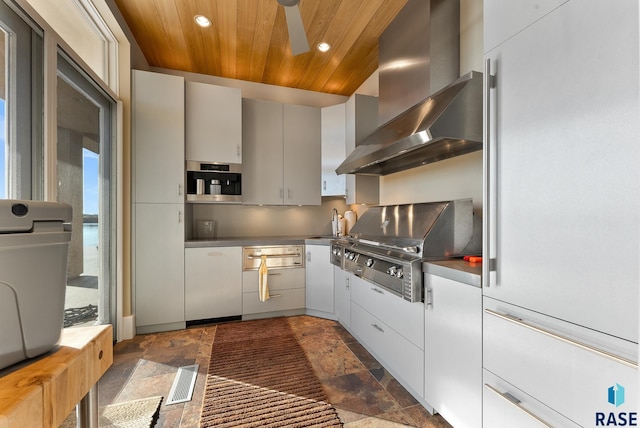 kitchen with ceiling fan, sink, wall chimney exhaust hood, and wooden ceiling