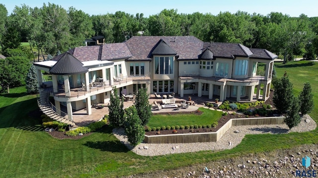 rear view of house with a lawn, a patio area, an outdoor hangout area, and a balcony