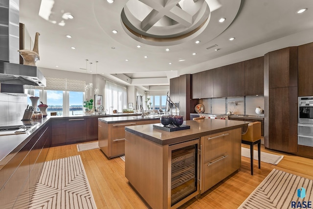 kitchen with a center island, beverage cooler, gas stovetop, kitchen peninsula, and decorative light fixtures