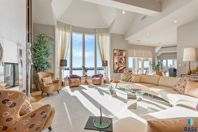 living room with hardwood / wood-style flooring, high vaulted ceiling, a water view, and a wealth of natural light