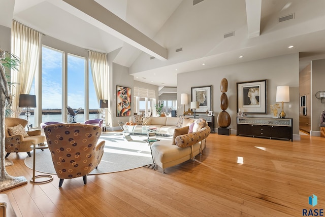 living room with beamed ceiling, a water view, light hardwood / wood-style floors, and high vaulted ceiling