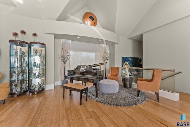 sitting room with light wood-type flooring and high vaulted ceiling