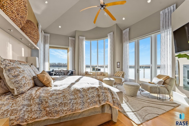 bedroom featuring access to outside, ceiling fan, a water view, high vaulted ceiling, and hardwood / wood-style floors