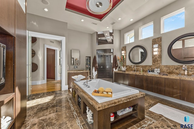 bathroom featuring a tray ceiling, a bathing tub, and vanity