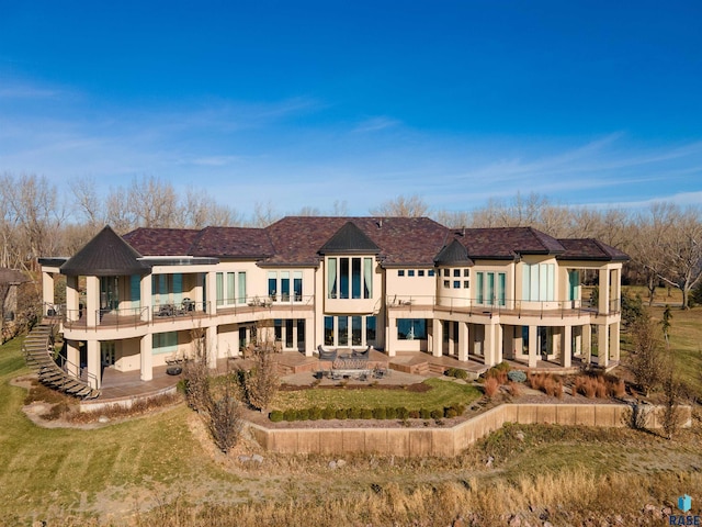 back of property featuring a yard, a patio, and a balcony