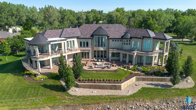 rear view of property featuring a lawn, a patio area, an outdoor living space, and a balcony