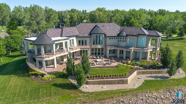 rear view of house with a patio area, a yard, and a balcony