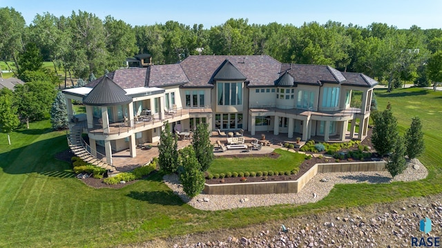 back of house with an outdoor living space, a patio area, a yard, and a balcony