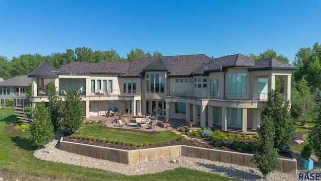 back of house featuring a yard, a patio area, an outdoor living space, and a balcony