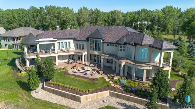 back of house with a lawn, an outdoor living space, a balcony, and a patio