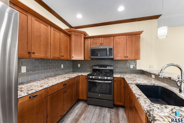 kitchen with appliances with stainless steel finishes, backsplash, sink, decorative light fixtures, and light hardwood / wood-style floors