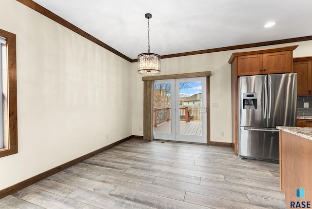 unfurnished dining area featuring a chandelier, light hardwood / wood-style flooring, and crown molding