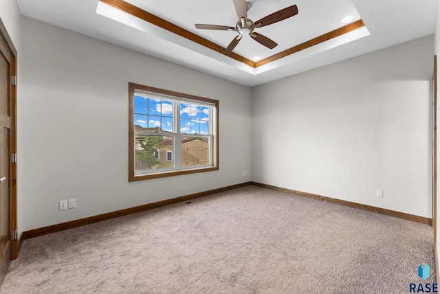 spare room featuring carpet flooring, ceiling fan, and a raised ceiling