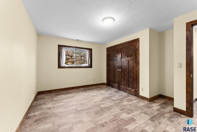 unfurnished bedroom with a closet, a textured ceiling, and light hardwood / wood-style flooring