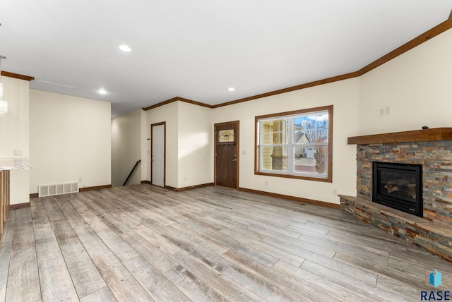 unfurnished living room featuring a stone fireplace, ornamental molding, and light hardwood / wood-style flooring