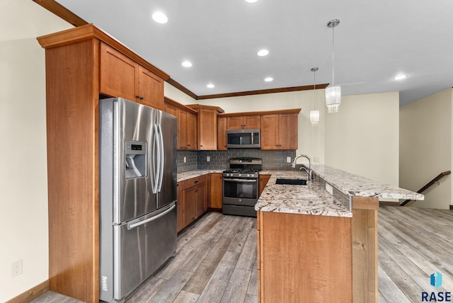 kitchen featuring sink, hanging light fixtures, appliances with stainless steel finishes, kitchen peninsula, and a breakfast bar area