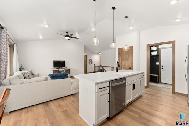 kitchen featuring sink, a center island with sink, dishwasher, white cabinetry, and hanging light fixtures