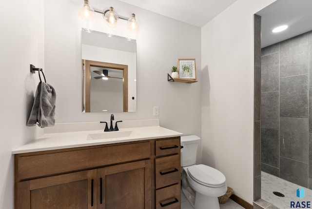 bathroom with toilet, ceiling fan, a tile shower, and vanity