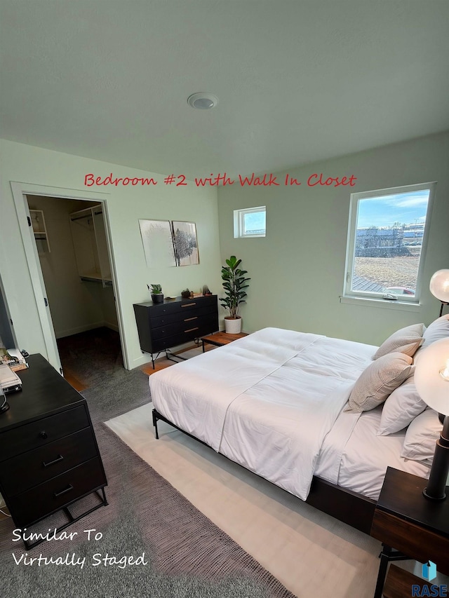 bedroom featuring a spacious closet, a closet, and dark carpet