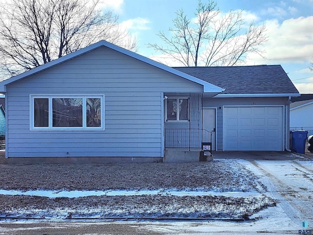 ranch-style home featuring an attached garage, driveway, and roof with shingles