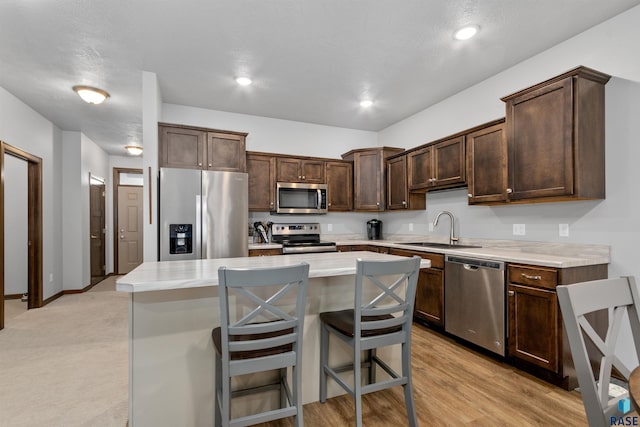 kitchen featuring a breakfast bar, dark brown cabinetry, stainless steel appliances, sink, and a center island