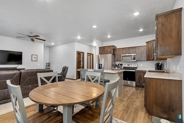 dining area featuring ceiling fan, sink, and light hardwood / wood-style floors