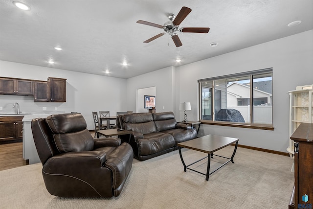 living room featuring ceiling fan, sink, and light colored carpet