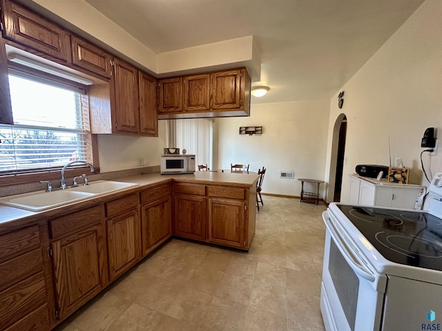 kitchen featuring kitchen peninsula, white appliances, and sink