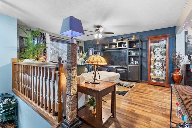 living room featuring wood-type flooring, a textured ceiling, and ceiling fan