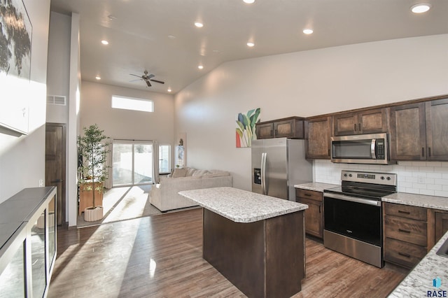 kitchen with ceiling fan, a center island, dark hardwood / wood-style flooring, high vaulted ceiling, and appliances with stainless steel finishes