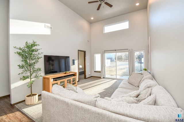 living room with a high ceiling, ceiling fan, and wood-type flooring