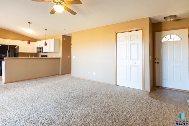 unfurnished living room featuring ceiling fan, light colored carpet, and vaulted ceiling