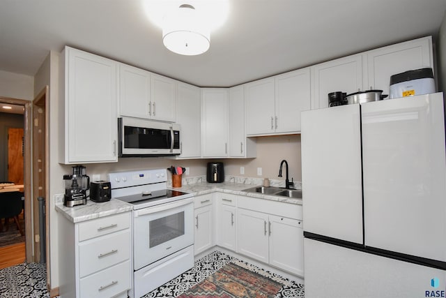 kitchen with white cabinetry, sink, light stone countertops, and white appliances