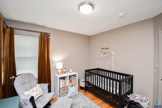 bedroom featuring a crib and hardwood / wood-style flooring