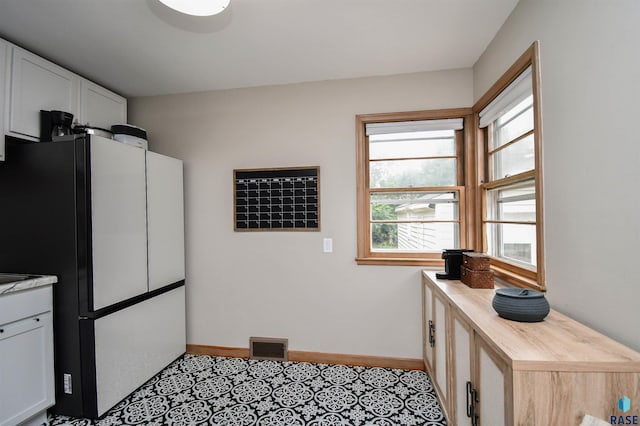 kitchen featuring white refrigerator, butcher block countertops, and white cabinetry