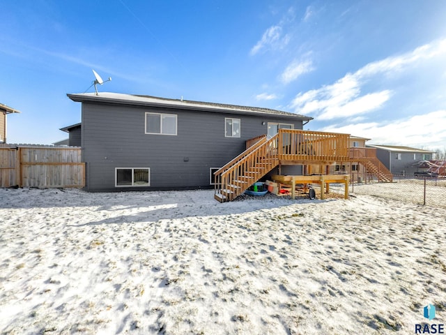 snow covered back of property with a wooden deck