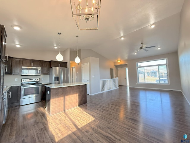 kitchen featuring decorative light fixtures, a center island, light stone counters, dark brown cabinetry, and appliances with stainless steel finishes